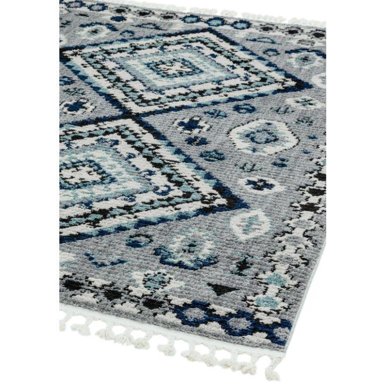 Grey and blue patterned area rug with geometric design and white tassel fringe