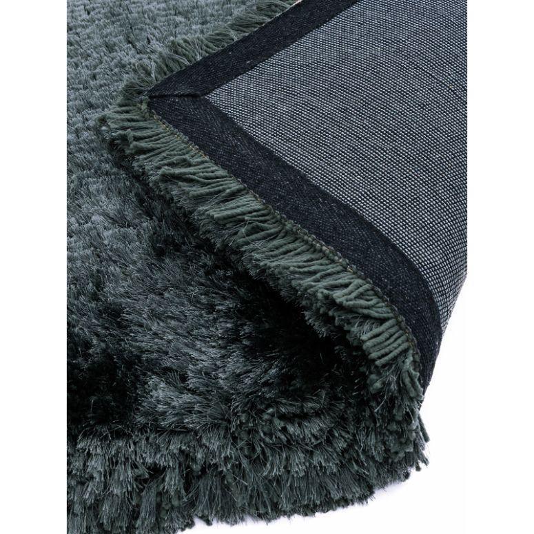 Close-up of dark green shaggy rug with thick pile and textured underside