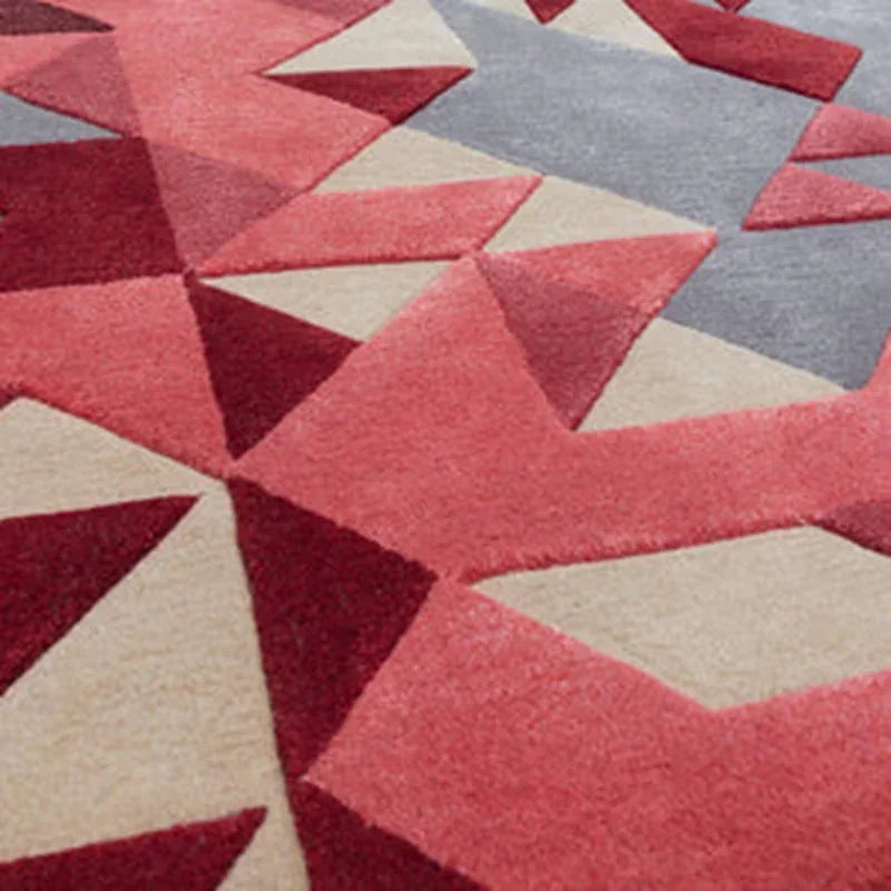 Geometric area rug with red, beige, and grey angular pattern, close-up of textured surface