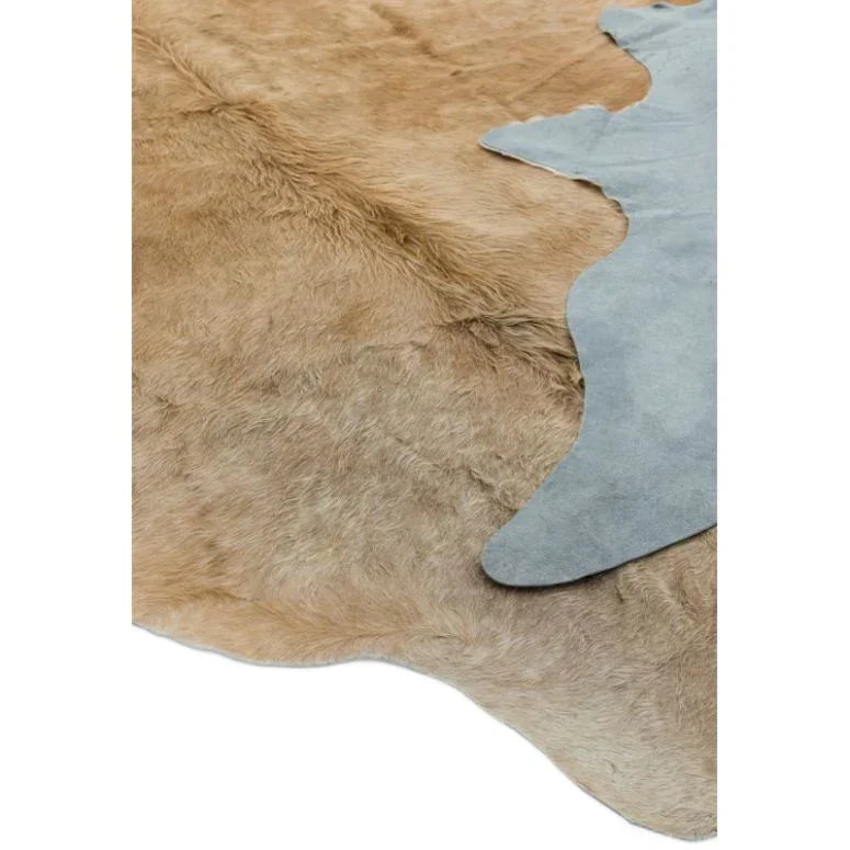 Light brown cowhide rug with natural fur texture and suede backing, close-up view