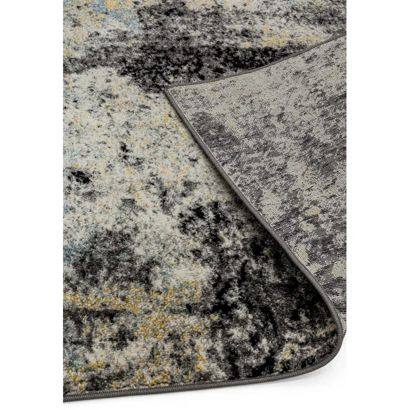 Modern area rug with grey, yellow, and blue abstract pattern, corner flipped to show backing