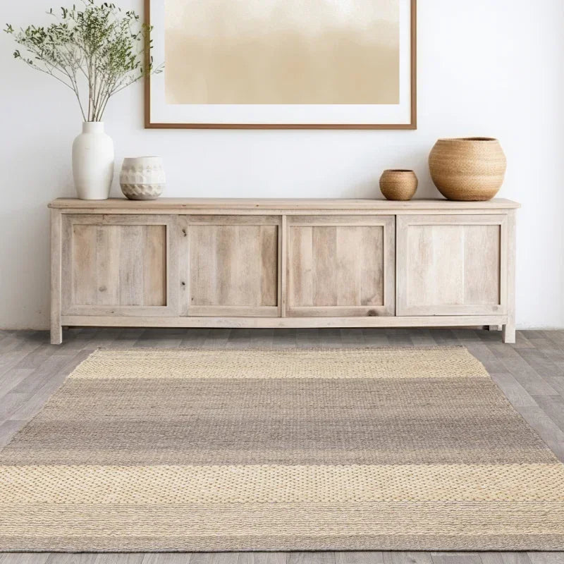 Neutral jute rug on wood floor with light wood sideboard and decorative vases