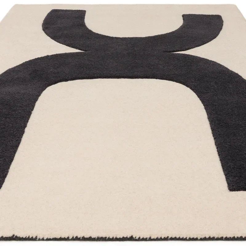 Modern area rug with bold black abstract pattern on cream background, closeup angle