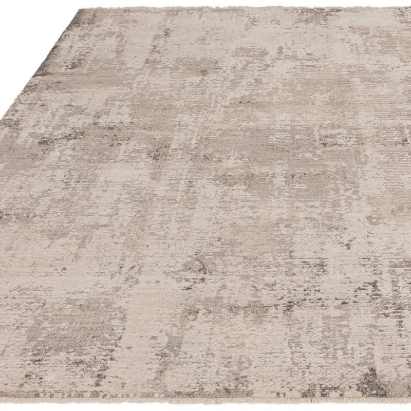 Neutral abstract area rug with textured beige and grey pattern, low angle view