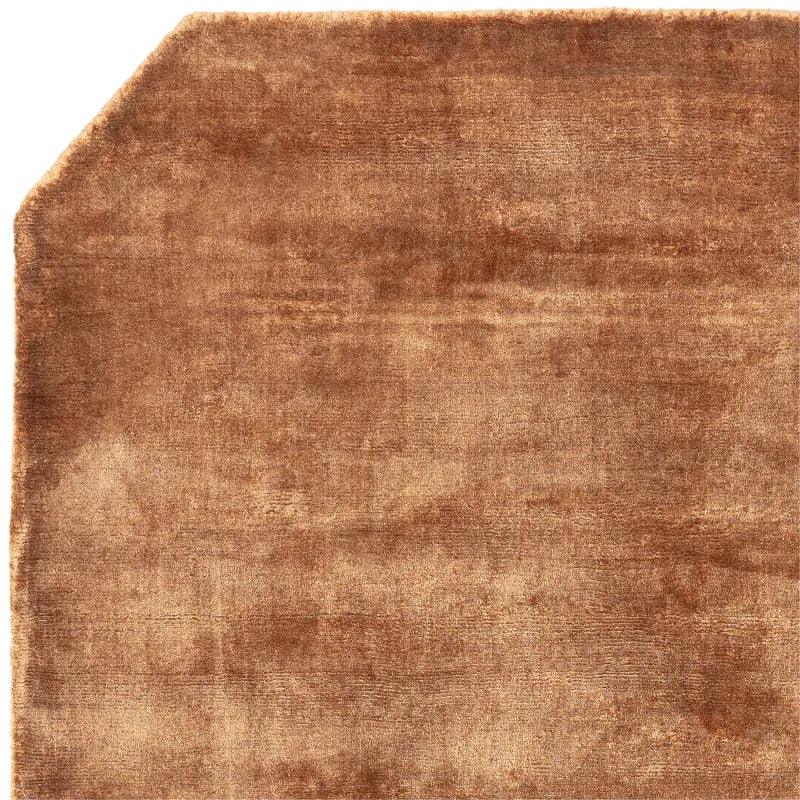 Brown velvet area rug with angled corner and soft textured surface