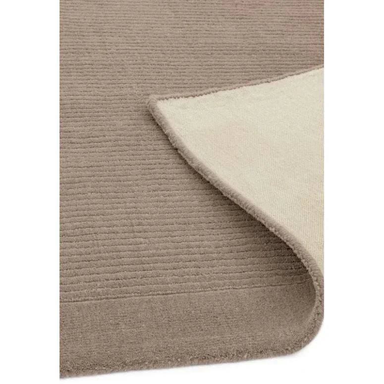 Beige textured rug with corner flipped, showing soft backing and ribbed surface design