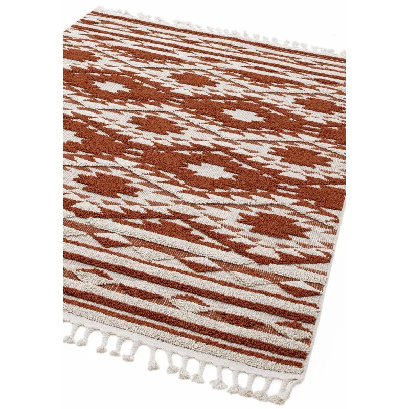 Rust geometric patterned rug with white tassels and textured woven design