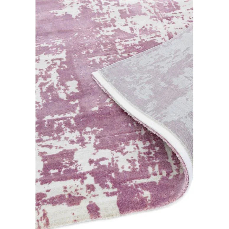 Purple abstract pattern area rug with corner flipped to show backing