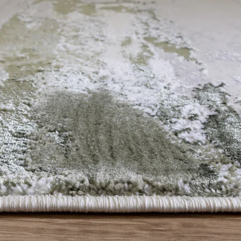 Close-up of modern abstract area rug with green and cream tones on wood floor