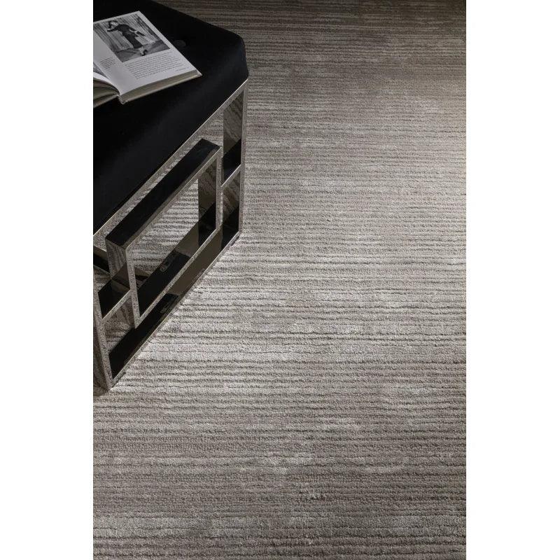 Textured grey area rug with modern mirrored bench and open book in contemporary interior