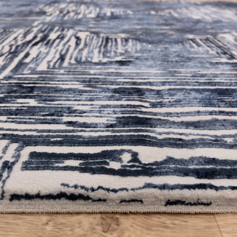 Blue and white abstract area rug on wooden floor, close-up of rug texture and edge