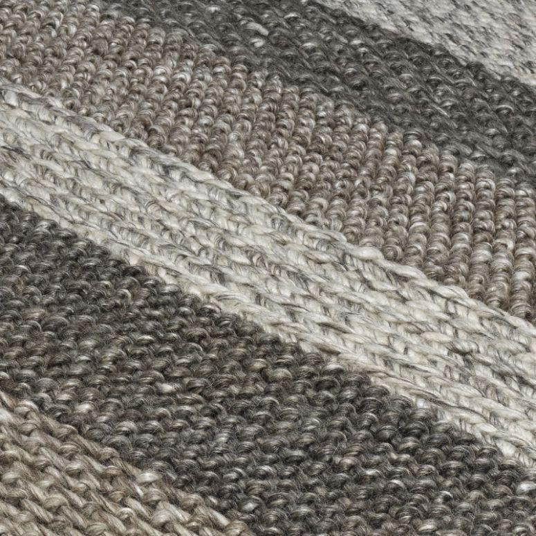 Closeup of woven rug with textured grey, beige and cream stripes