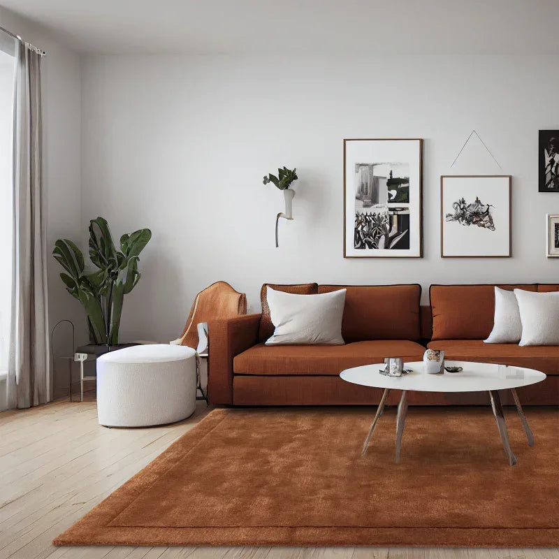 Brown fabric sofa with white cushions in modern living room, round coffee table and indoor plant