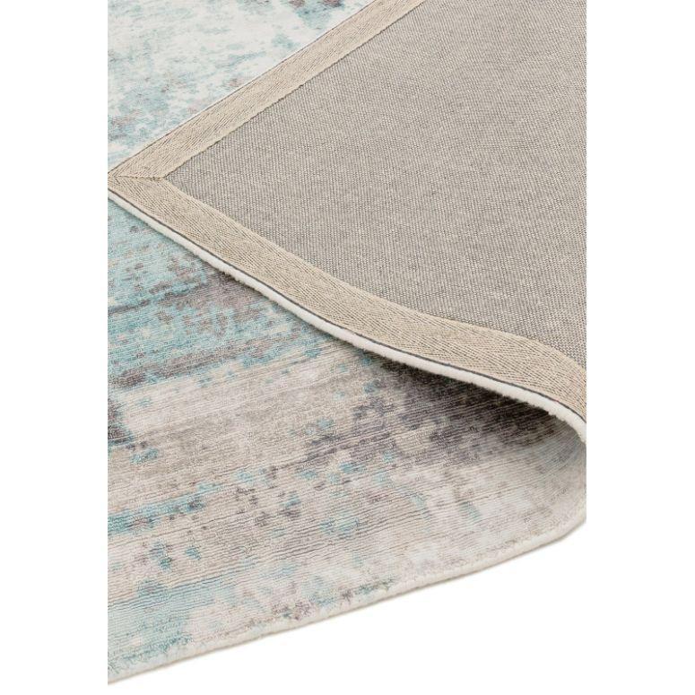 Blue and grey area rug with one corner flipped to show backing