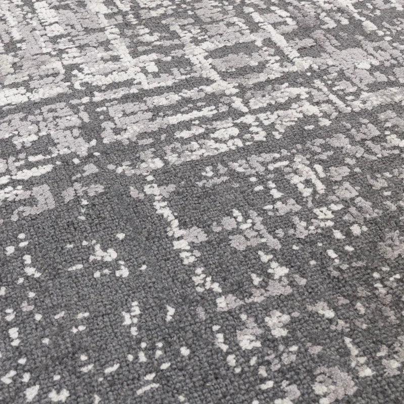 Grey patterned rug with textured surface and white geometric accents, close-up angle