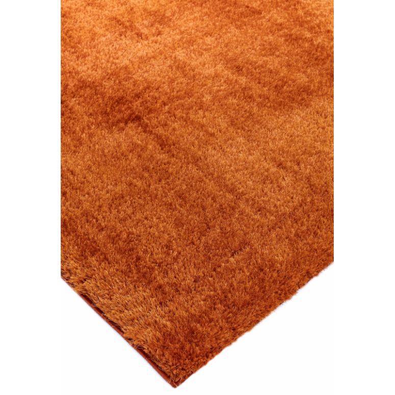 Corner view of orange shaggy rug with thick pile texture