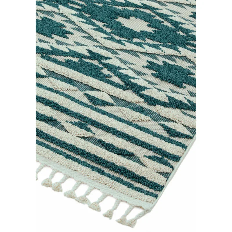Green and cream patterned rug with textured weave and fringe corner detail