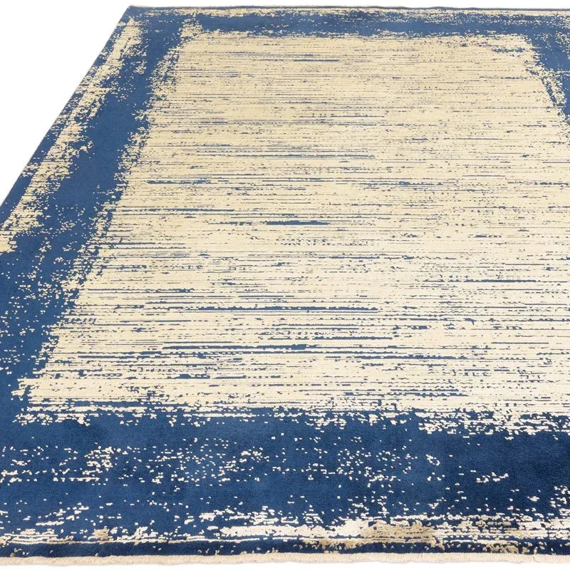 Blue and beige abstract rug with a textured border design on a flat surface