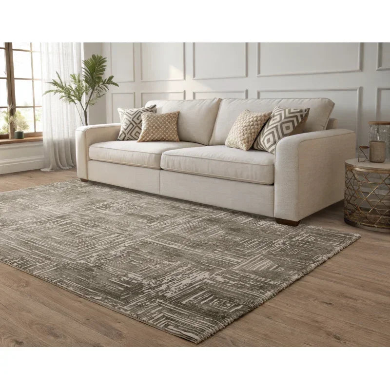 Beige fabric sofa with patterned cushions in living room on geometric grey area rug