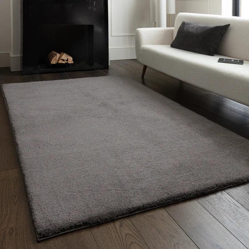 Grey area rug on dark wood flooring in modern living room with cream sofa