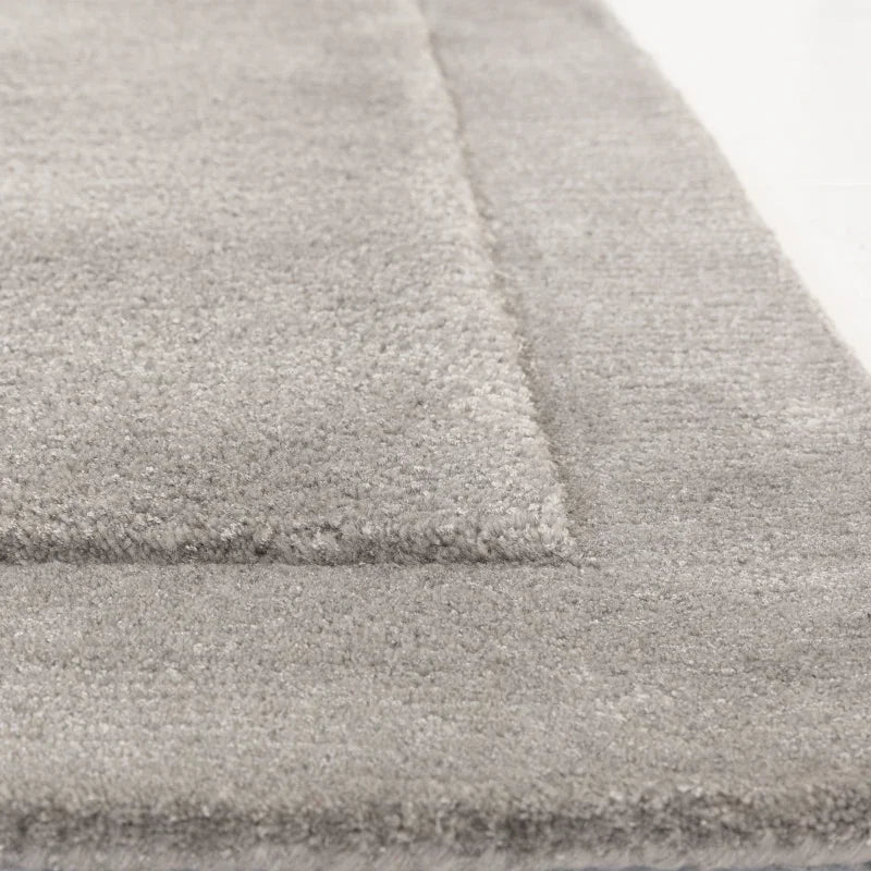 Close-up of light grey area rug with soft pile and raised border detail