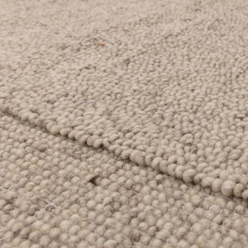 Closeup of beige wool loop pile rug texture and edge detail