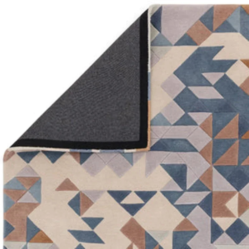 Geometric patterned rug in blue, beige and brown with corner flipped to show backing