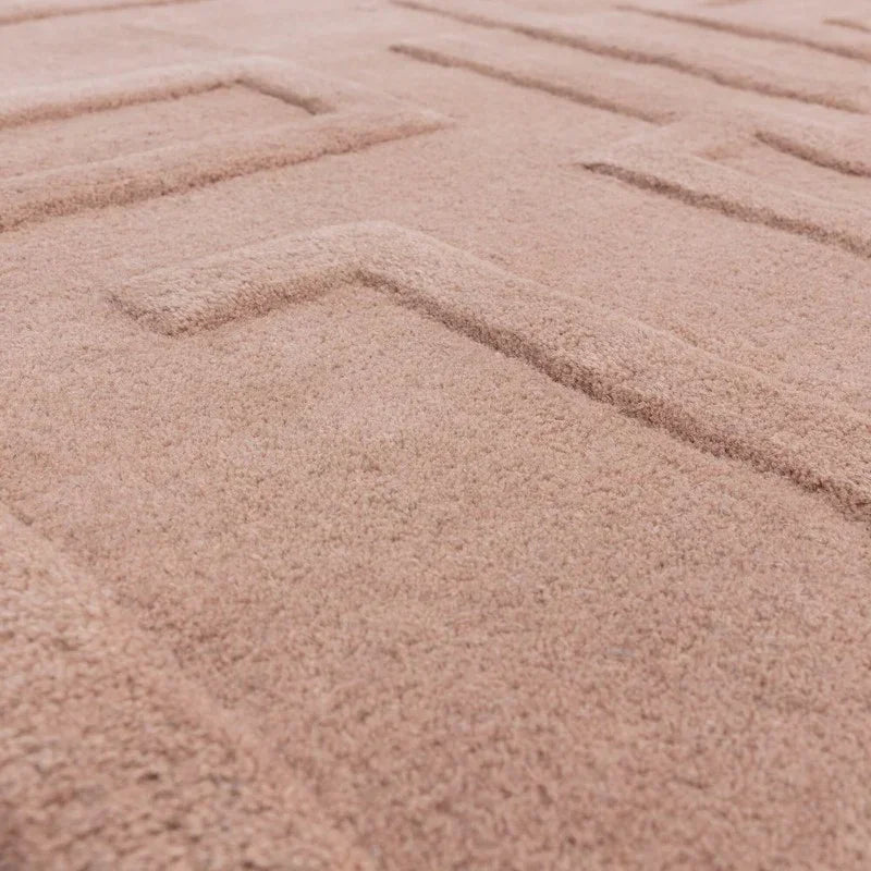 Blush pink textured rug with geometric raised pattern, close-up view of fabric detail