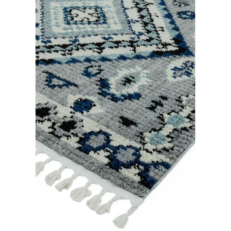 Grey and blue patterned rug corner with geometric designs and white fringe