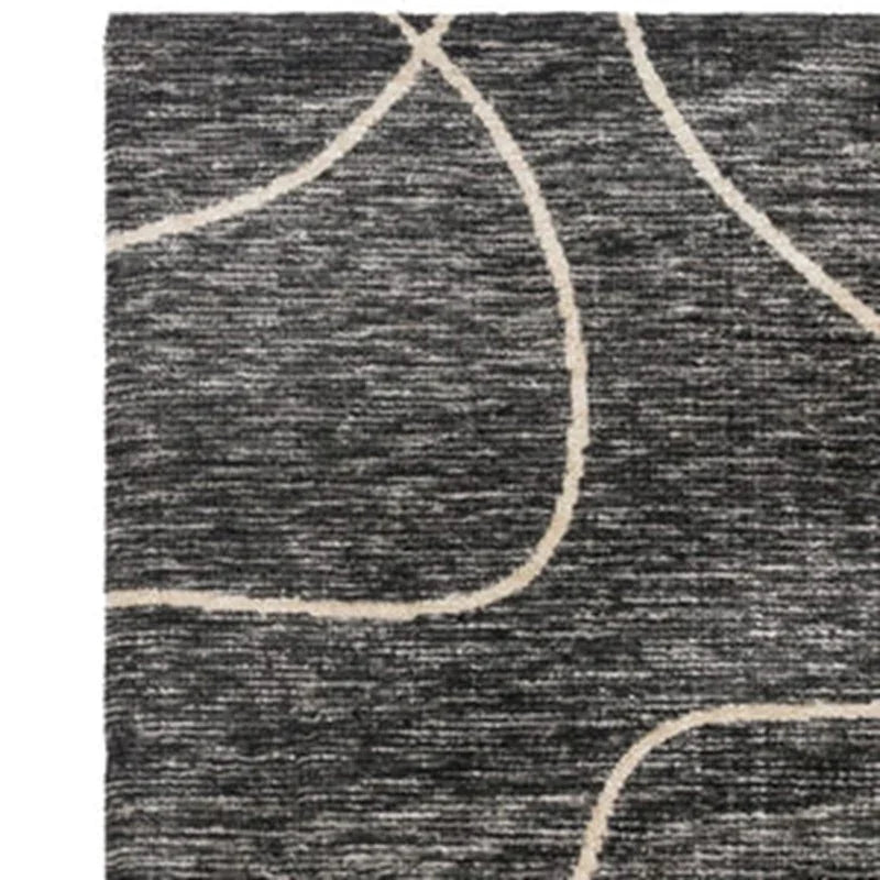 Grey area rug with abstract cream curved line pattern, close-up view of corner