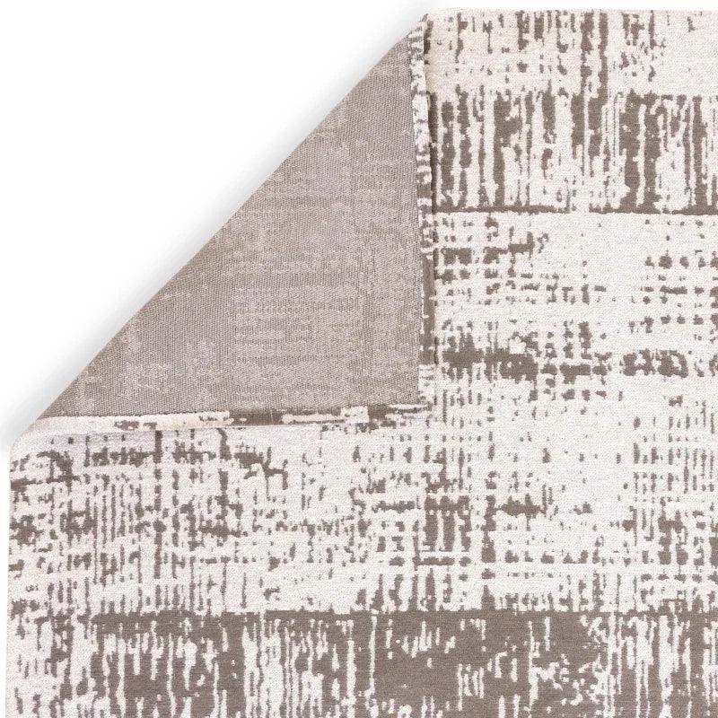 Beige and taupe abstract area rug corner fold showing textured surface detail