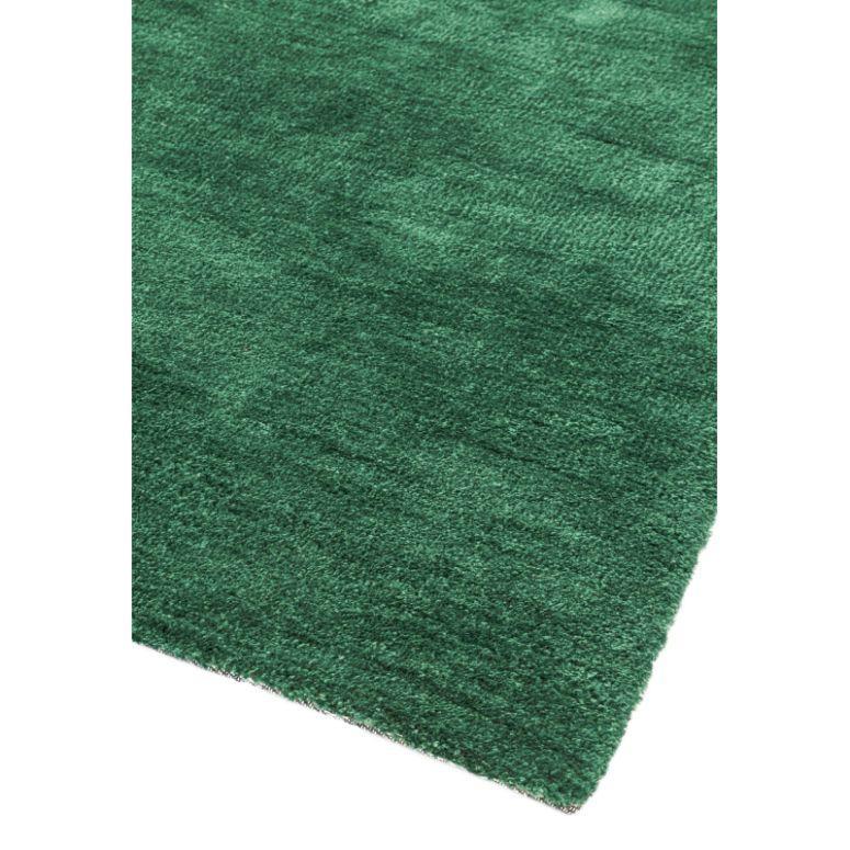 Close view of green area rug with textured pile and finished edge