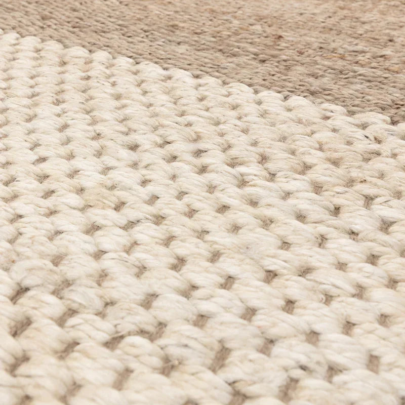 Close up of woven wool rug in cream and beige tones showing texture and pattern