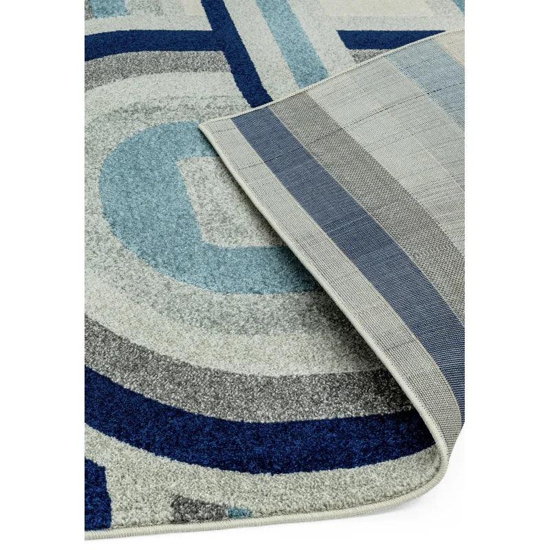Blue and grey patterned area rug with corner flipped to show backing detail