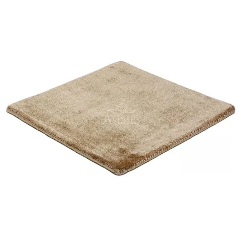 Square beige rug with soft pile and stitched edges, viewed from an angle
