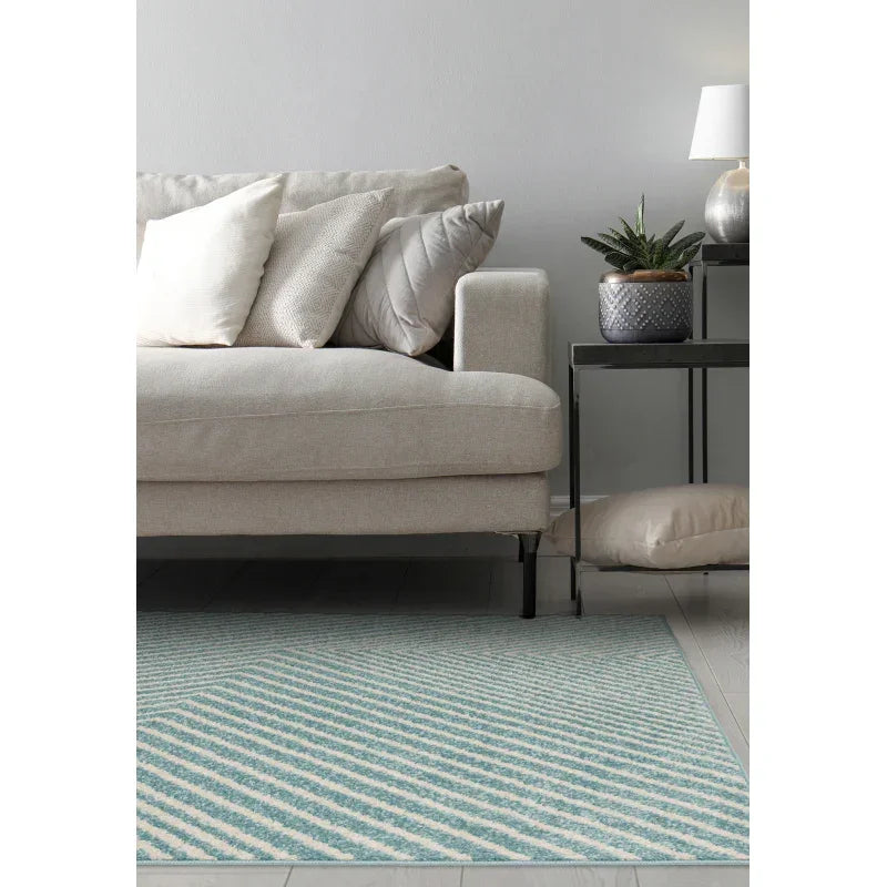 Beige fabric sofa with striped cushions, side table, indoor plant, and blue patterned rug