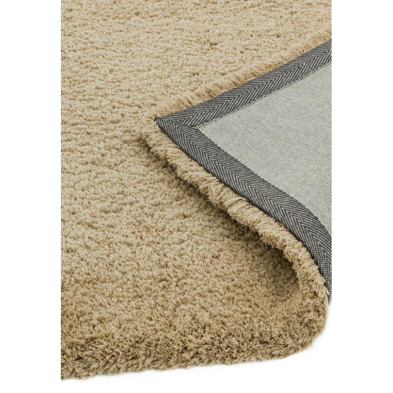 Beige shaggy rug with visible textured pile and corner showing contrasting fabric backing