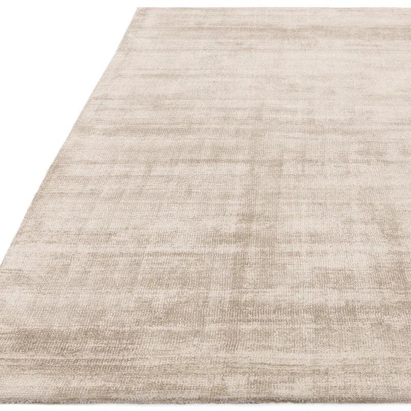 Beige area rug with subtle textured pattern and soft finish, shown from corner angle