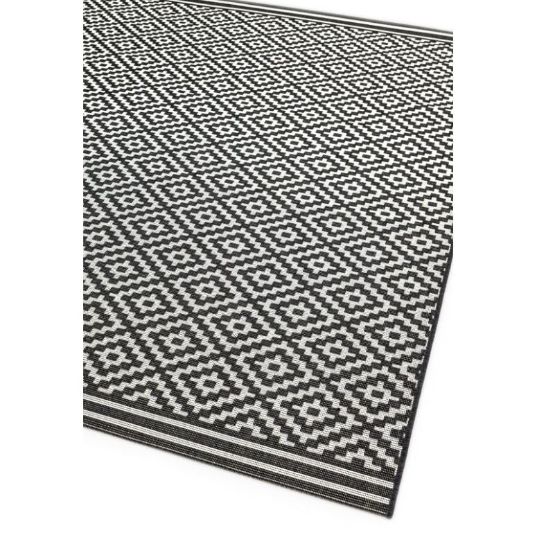 Black and white geometric patterned rug with diamond motifs and striped border