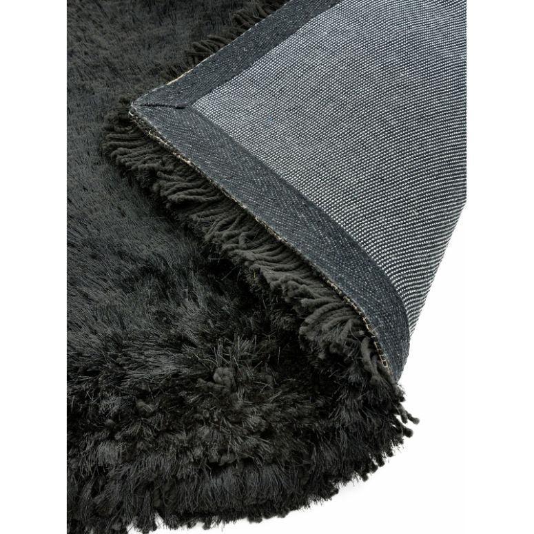 Close-up of black shaggy rug with corner flipped to show backing and texture