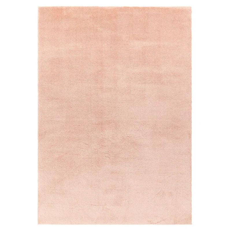 Rectangular blush pink area rug with soft, plush texture and plain design