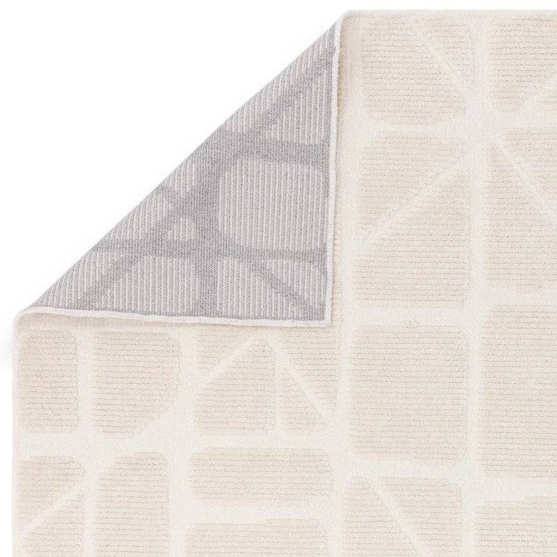 Cream geometric rug with textured pattern and folded grey corner detail