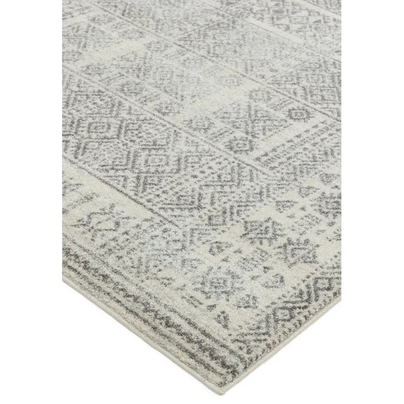 Grey patterned area rug with geometric design and textured surface corner view