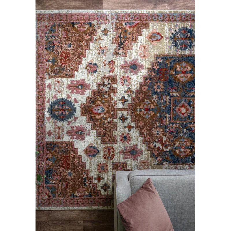 Patterned area rug with multicolor geometric and floral design beside a grey sofa