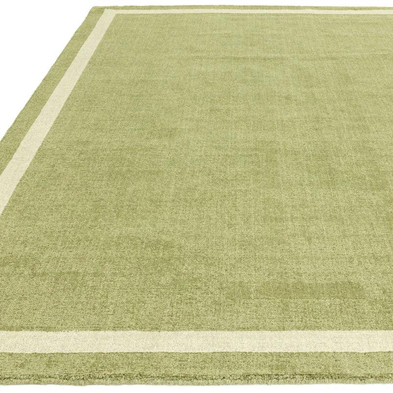 Green area rug with cream border detail, low-pile texture, rectangular design