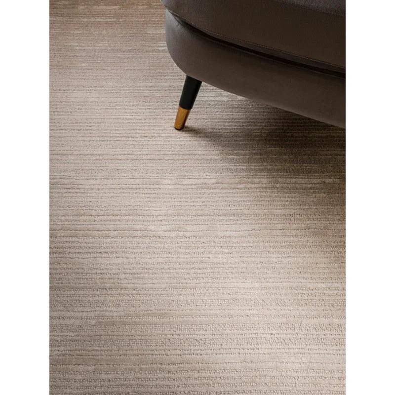 Beige textured rug under corner of brown fabric sofa with black and gold tapered leg