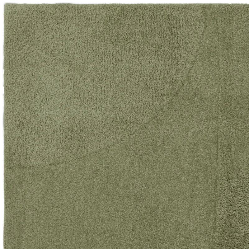 Green textured rug with subtle curved geometric pattern, close-up of corner and pile