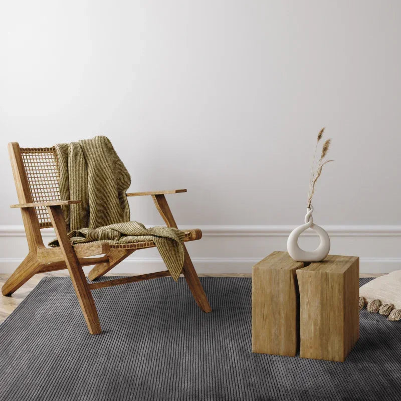 Wooden accent chair with woven backrest and throw blanket beside rustic coffee table on grey rug