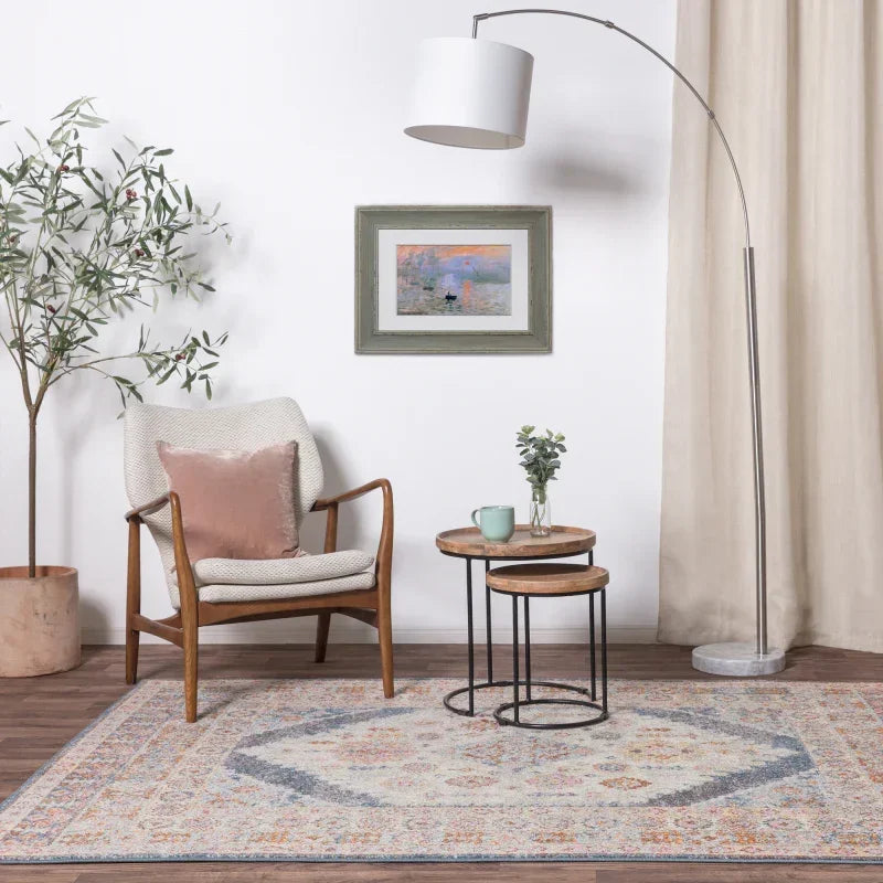 Scandi armchair with cushion, nesting tables, and patterned rug in modern living room setup