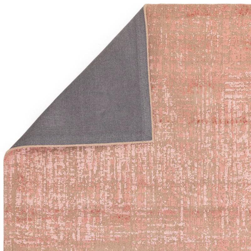 Textured pink area rug with corner flipped to show grey non-slip backing